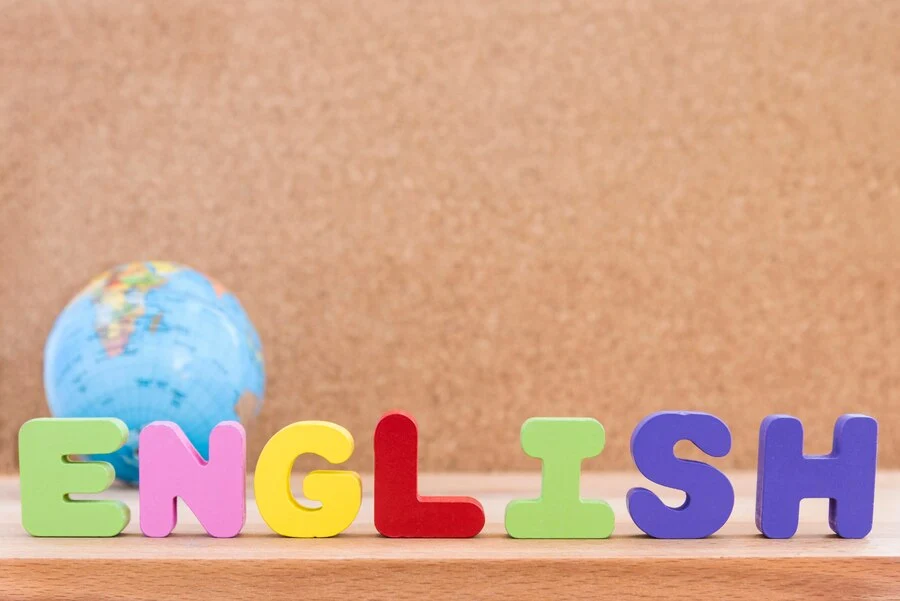 Letras coloridas formando a palavra "ENGLISH" com um globo ao fundo, representando Aulas de ESL (English as a Second Language).