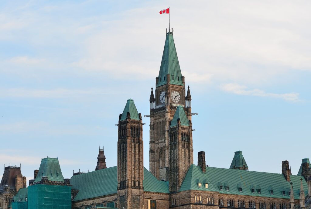 Torre icônica do Parlamento do Canadá em Ottawa com a bandeira nacional ao topo, representando a identidade e o patrimônio cultural do país.