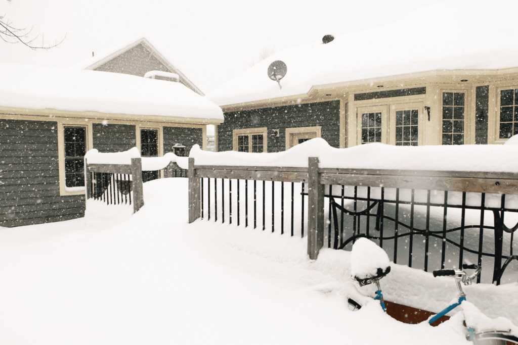 Outdoor area covered in snow a student dormitory during the winter, with a bicycle partially buried in the snow.