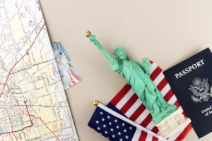 United States passport next to Statue of Liberty, American flag, map and permanent residence card.