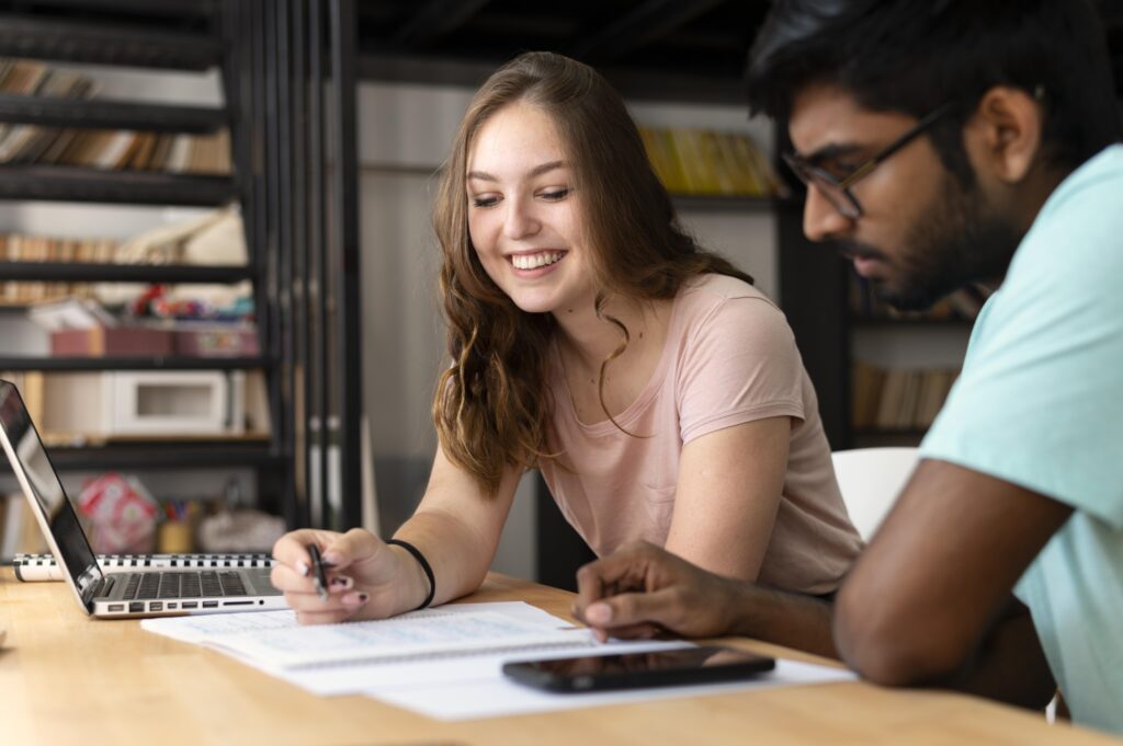 Dos estudiantes estudiando juntos y revisando información académica